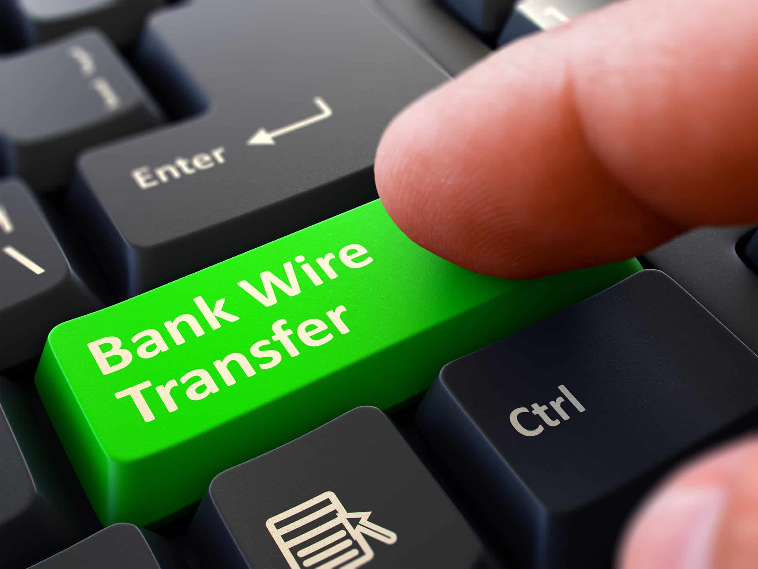One Finger Presses Green Button Bank Wire Transfer on Black Computer Keyboard. Closeup View. Selective Focus.